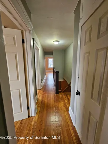 a view of a hallway with wooden floor and staircase