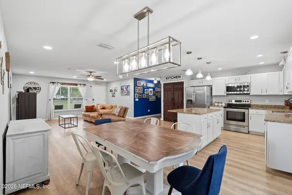 a living room with stainless steel appliances furniture a dining table and chairs