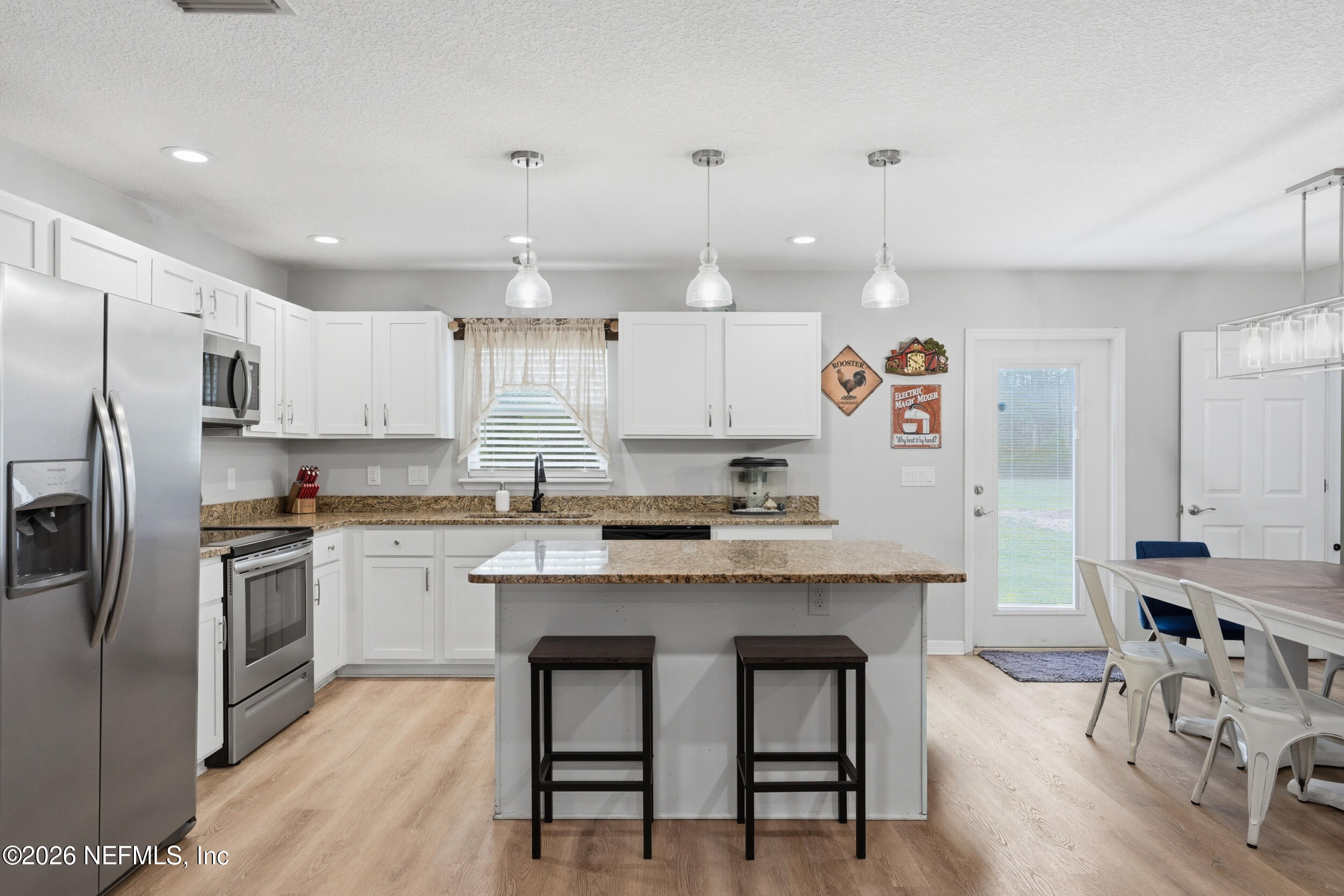 2471 Iris Street Middleburg, FL 32068 - Photo 6 of 40 a kitchen with kitchen island granite countertop a sink a center island and stainless steel appliances