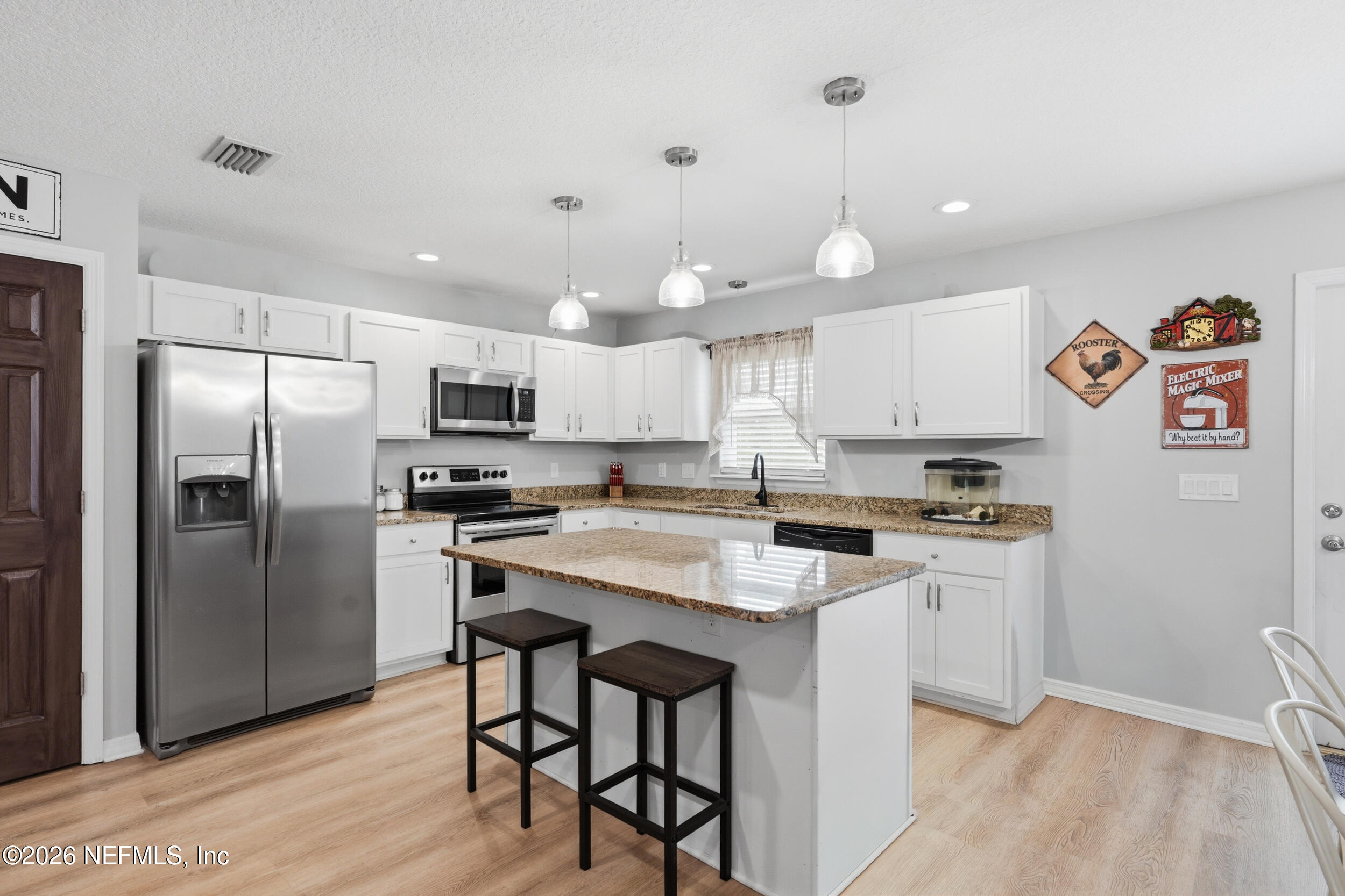 2471 Iris Street Middleburg, FL 32068 - Photo 7 of 40 a kitchen with stainless steel appliances granite countertop a refrigerator a sink dishwasher a stove and white cabinets with wooden floor