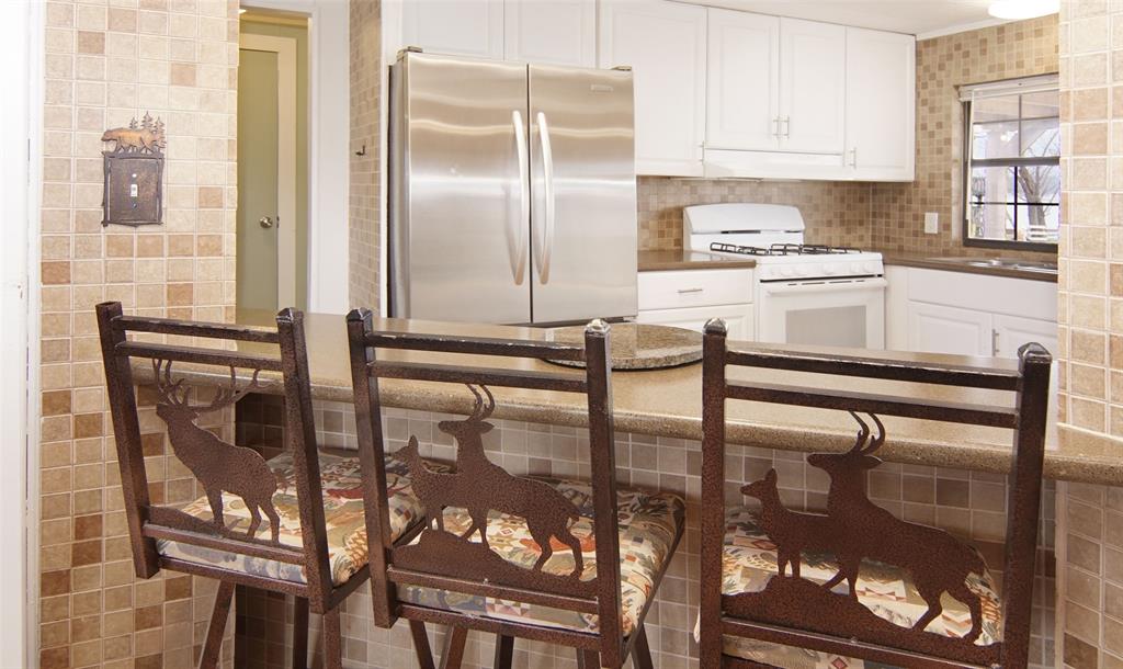 1059 Airport Road Graford, TX 76449 - Photo 12 of 37 Kitchen with tasteful backsplash, white gas range, white cabinetry, and freestanding refrigerator
