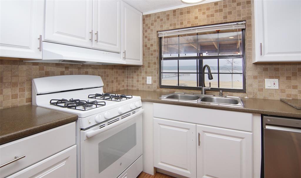 1059 Airport Road Graford, TX 76449 - Photo 14 of 37 Kitchen featuring stainless steel dishwasher, white cabinets, white range with gas cooktop, a sink, and under cabinet range hood
