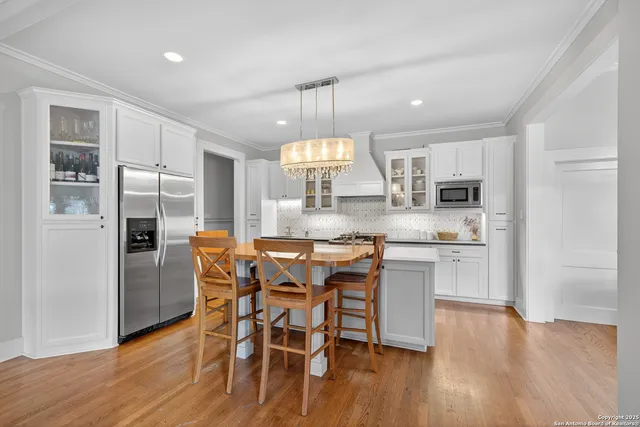 a kitchen with kitchen island granite countertop wooden floors and refrigerator