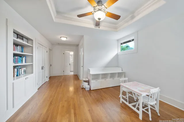 a view of empty room with wooden floor and fan