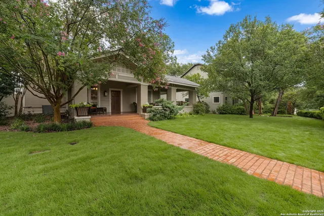 a view of house with a big yard and large trees