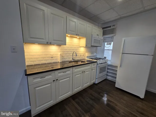 a kitchen with granite countertop white cabinets and white appliances