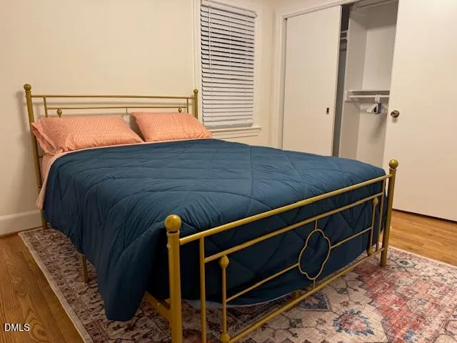a bed sitting in a bedroom next to a window with wooden floor
