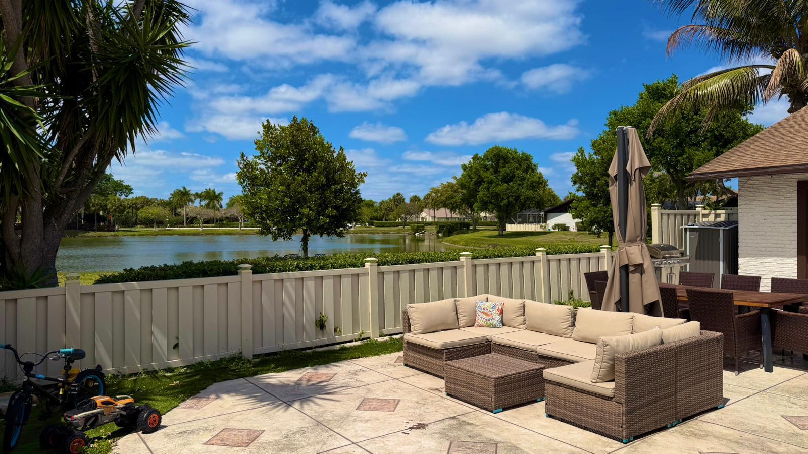 9903 Boca Gardens Trail Boca Raton, FL 33496 - Photo 6 of 37 a view of a patio with couches chairs and a floor to ceiling window next to a yard