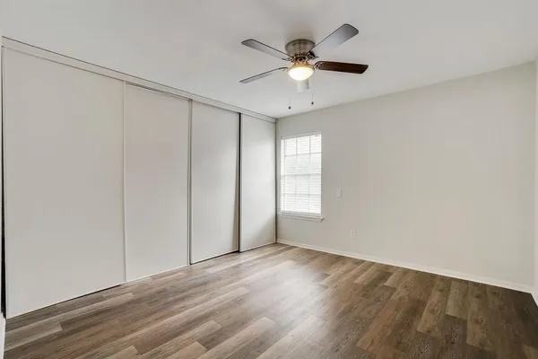 an empty room with wooden floor fan and windows