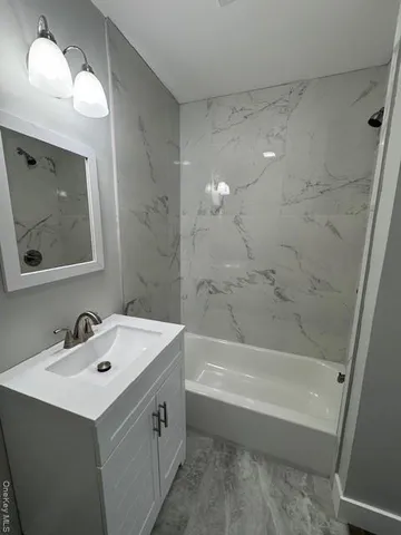 a bathroom with a sink mirror vanity and bathtub
