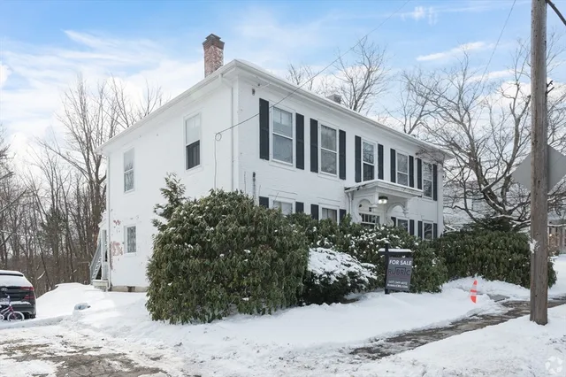 a front view of a house with a yard covered in snow