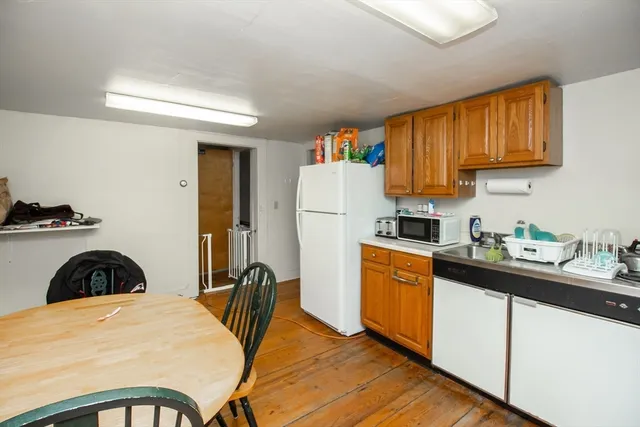 a kitchen with granite countertop a refrigerator a stove a sink dishwasher and wooden cabinets with wooden floor