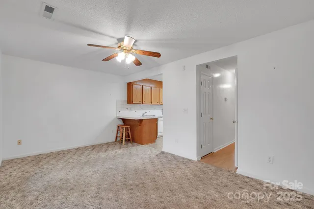 a view of an empty room and chandelier fan