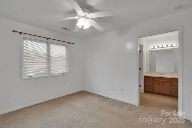 a view of an empty room with chandelier fan and fire place