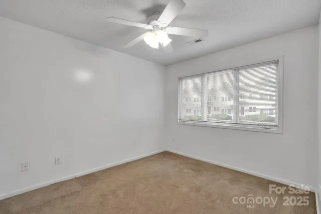 an empty room with windows and ceiling fan