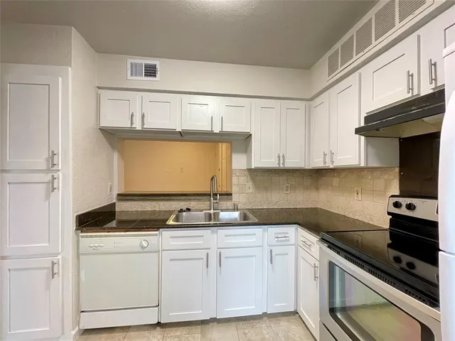 a kitchen with granite countertop a sink stove and cabinets
