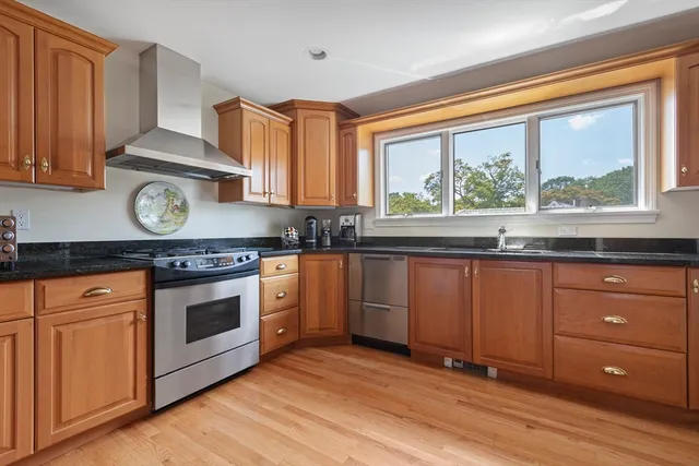 a kitchen with granite countertop wooden cabinets stainless steel appliances and a large window