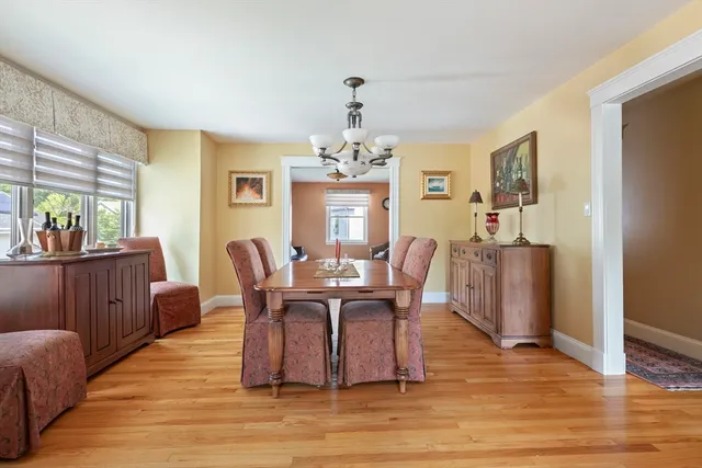 a dining room with wooden floor a chandelier a wooden table and chairs