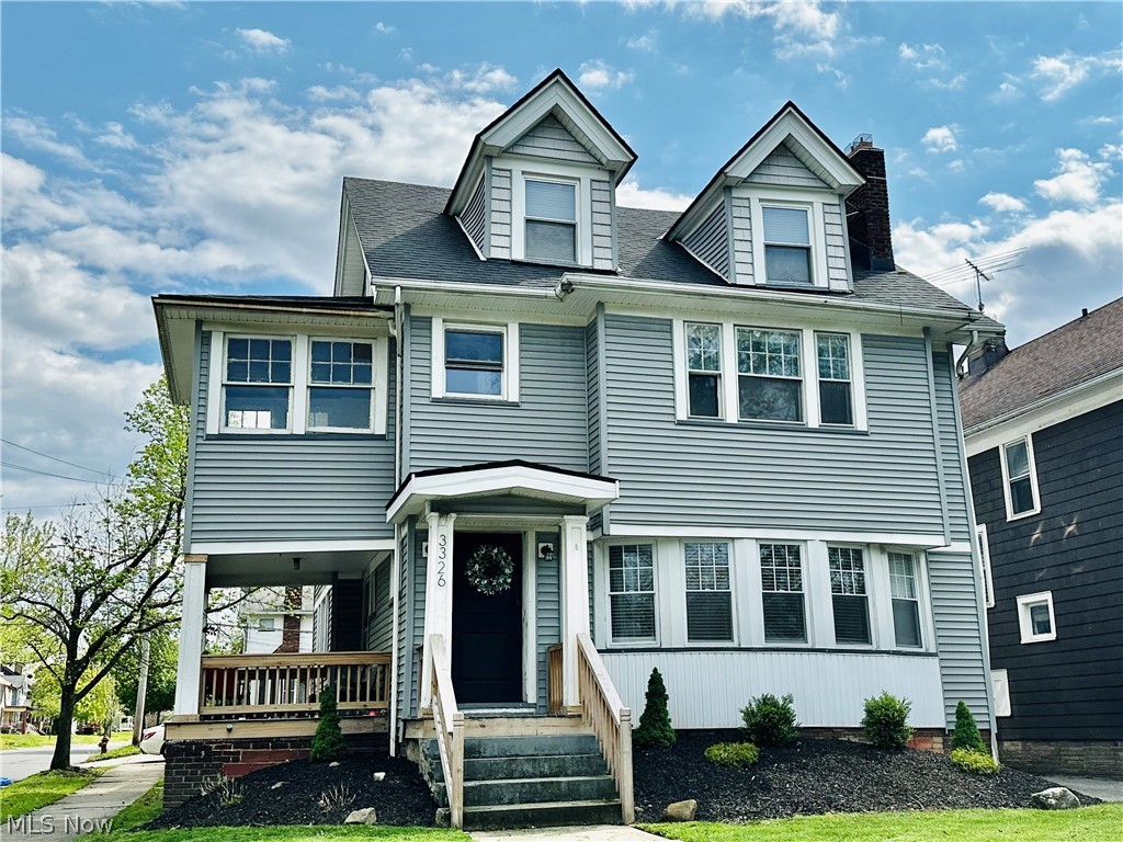 3326 East Overlook Road Cleveland Heights, OH 44118 - Photo 1 of 29 Light gray siding exterior featuring dormer windows, a covered front porch, and mature landscaping