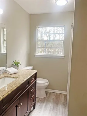 a bathroom with a granite countertop toilet sink and window