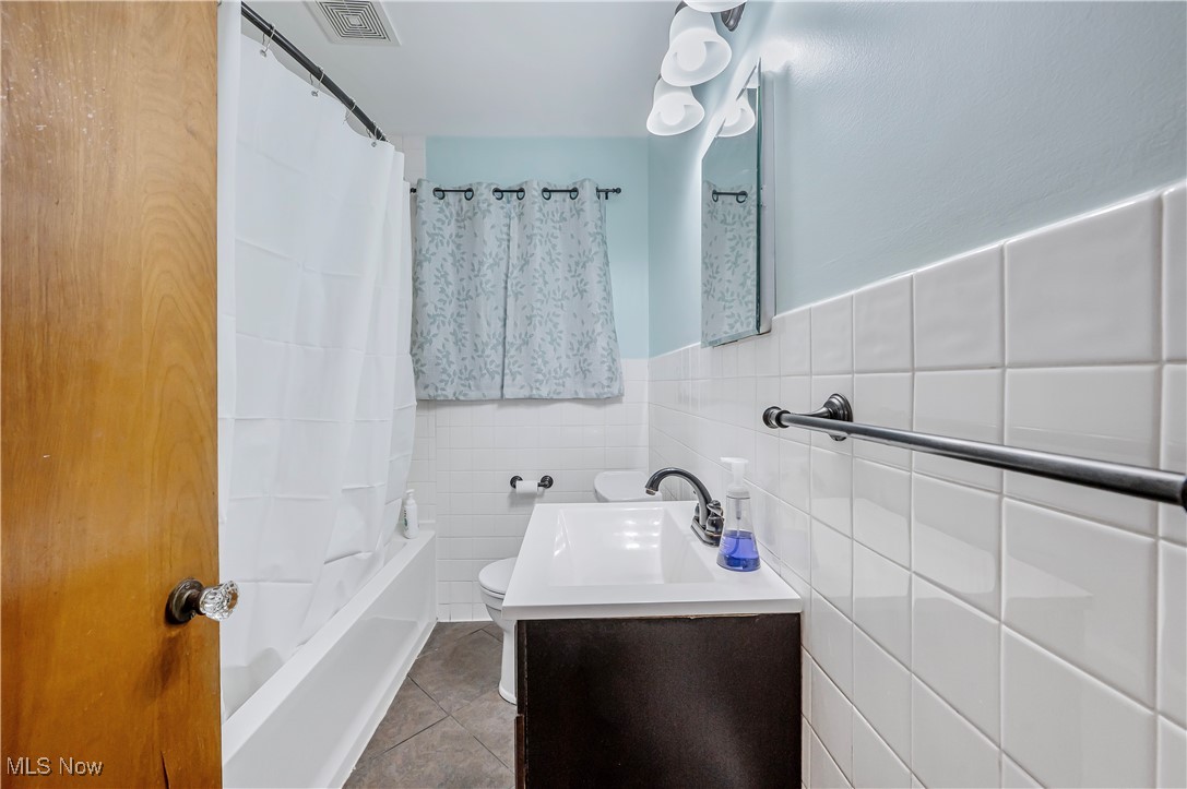 3000 19th Street Northwest Canton, OH 44708 - Photo 6 of 19 Full bathroom featuring tile patterned floors, vanity, shower / tub combo with curtain, tile walls, and toilet