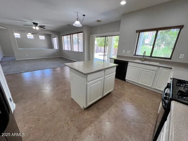 a view of a kitchen island a large window a sink and cabinets