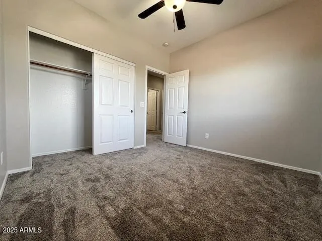 an empty room with a ceiling fan and carpet