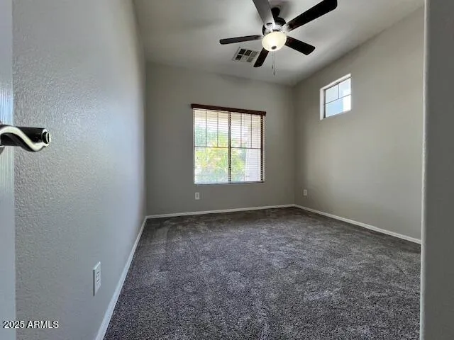an empty room with windows and fan