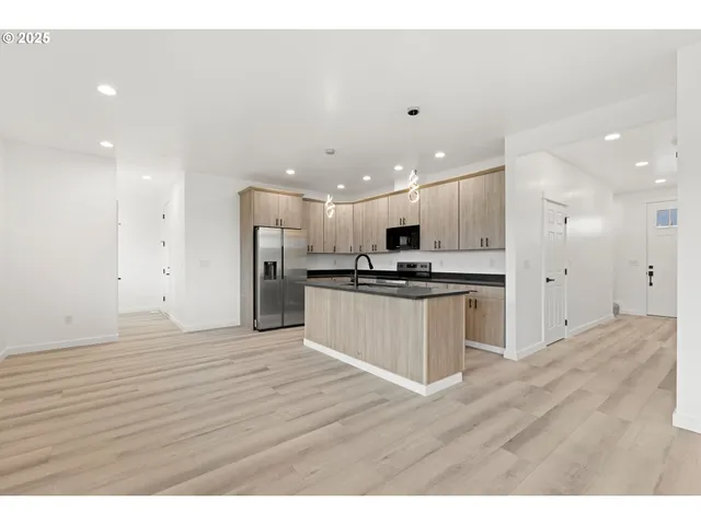 a view of kitchen with granite countertop refrigerator and white cabinets