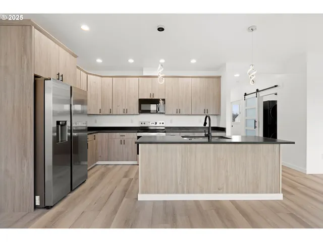 a kitchen with stainless steel appliances granite countertop a refrigerator a sink a stove and a microwave