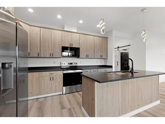a kitchen with kitchen island granite countertop a sink cabinets and stainless steel appliances