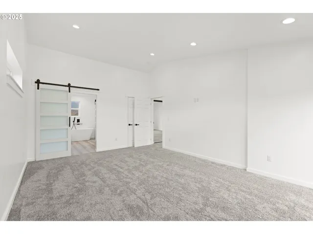 a view of an empty room with wooden floor and windows