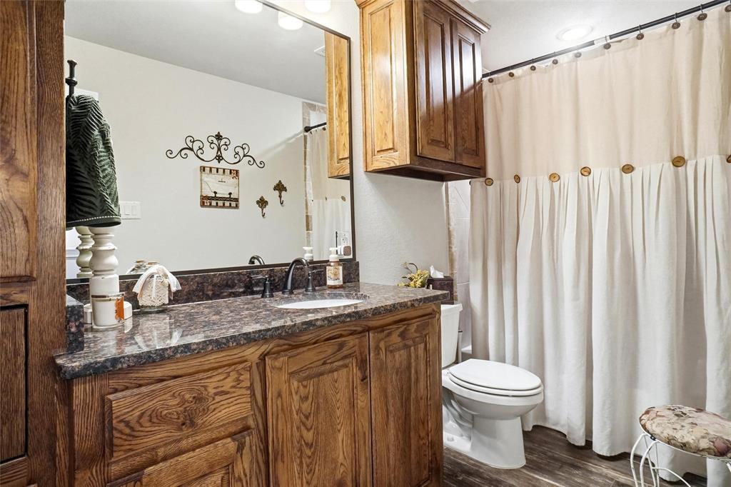 1024 Tex Lane Springtown, TX 76082 - Photo 32 of 40 a bathroom with a granite countertop sink a toilet and a mirror