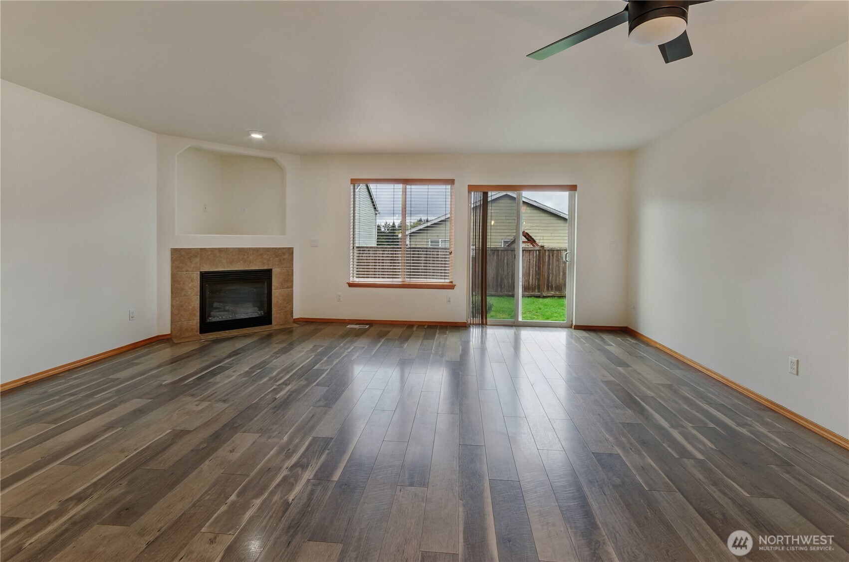 9114 Canal Road Southeast Yelm, WA 98597 - Photo 13 of 40 an empty room with wooden floor fireplace and windows