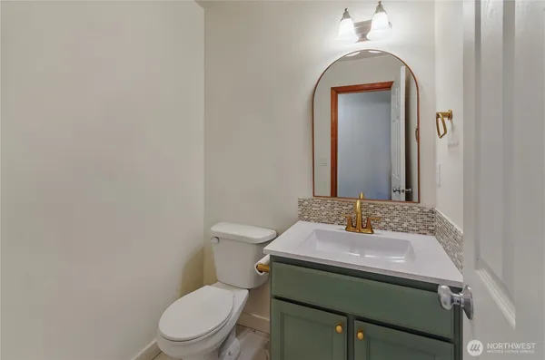 a bathroom with a toilet sink vanity and mirror