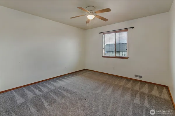 an empty room with windows and fan