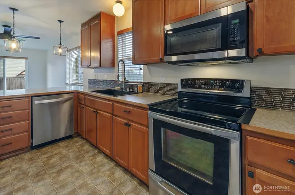 a kitchen with stainless steel appliances a stove a microwave a sink and cabinets