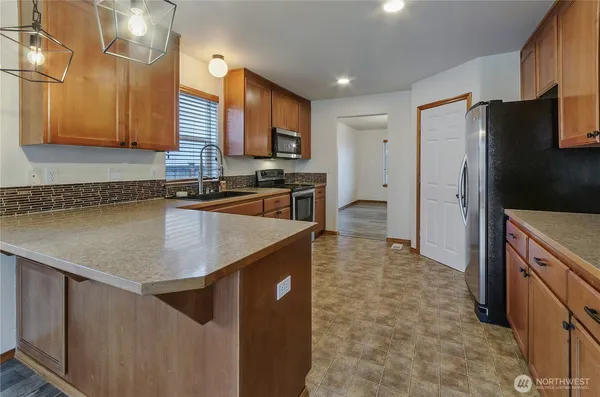 a kitchen with stainless steel appliances granite countertop a sink a stove a refrigerator a washer and dryer