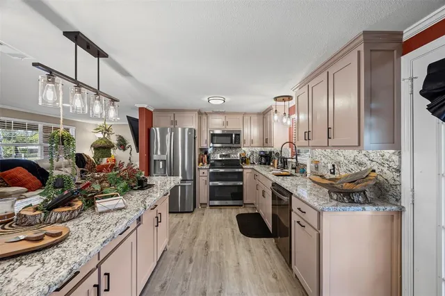 a kitchen with stainless steel appliances granite countertop a stove top oven a sink dishwasher and a refrigerator with wooden floor