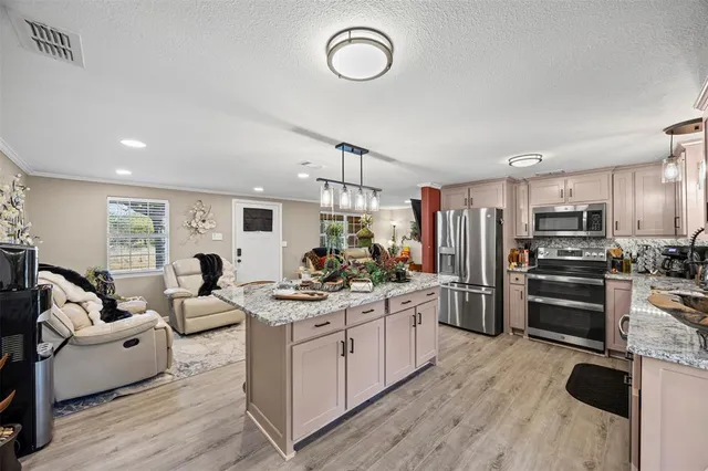 a kitchen with refrigerator a stove a sink dishwasher a dining table and chairs with wooden floor