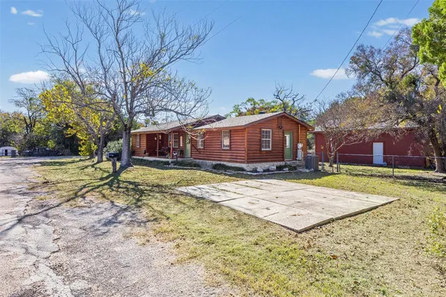 a view of a house with a yard and large tree