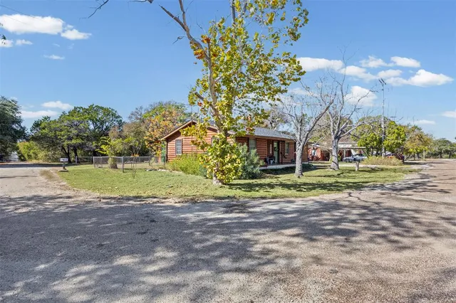 a view of a house with a big yard and large trees
