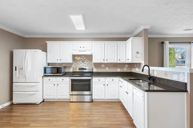 a kitchen with granite countertop white cabinets and white appliances