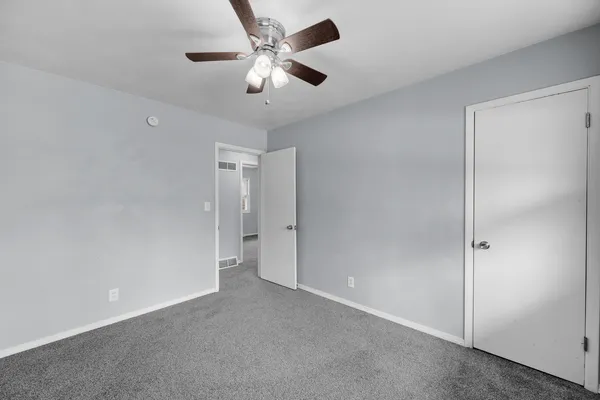 an empty room with chandelier fan and closet