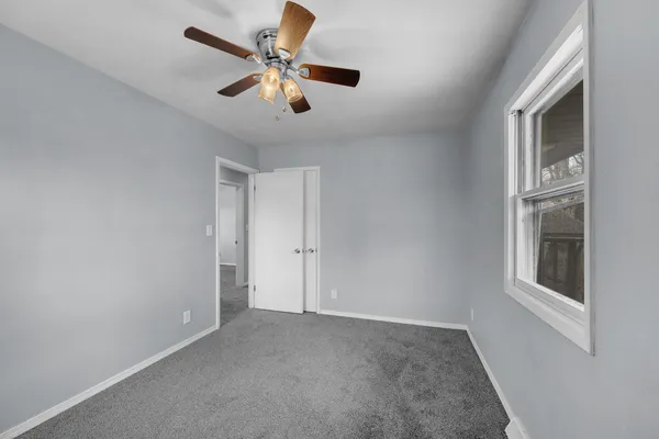an empty room with windows and fan