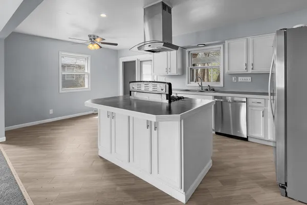 a kitchen with stainless steel appliances granite countertop a sink and dishwasher a refrigerator with wooden floors