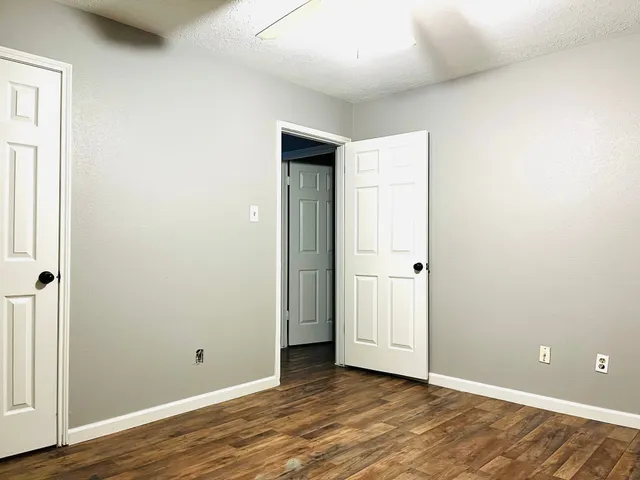a view of an empty room with wooden floor and closet