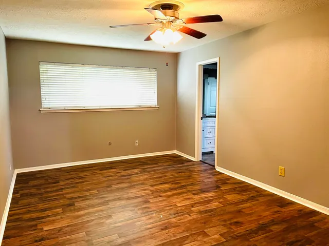 an empty room with a window and a ceiling fan