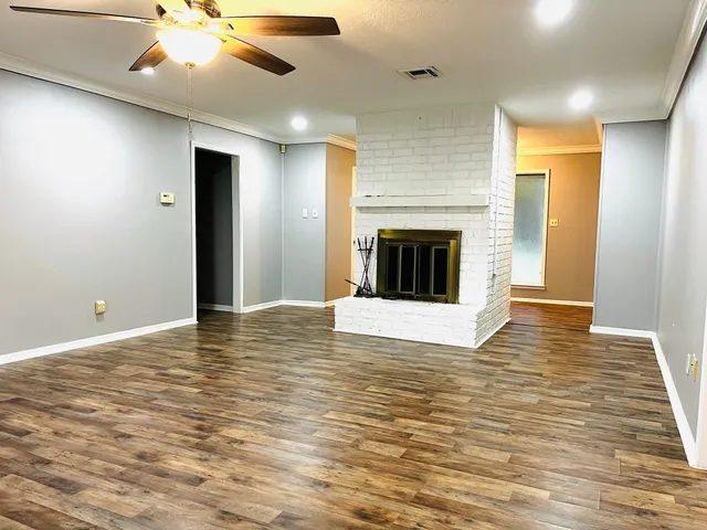 a view of an empty room with wooden floor and a fireplace