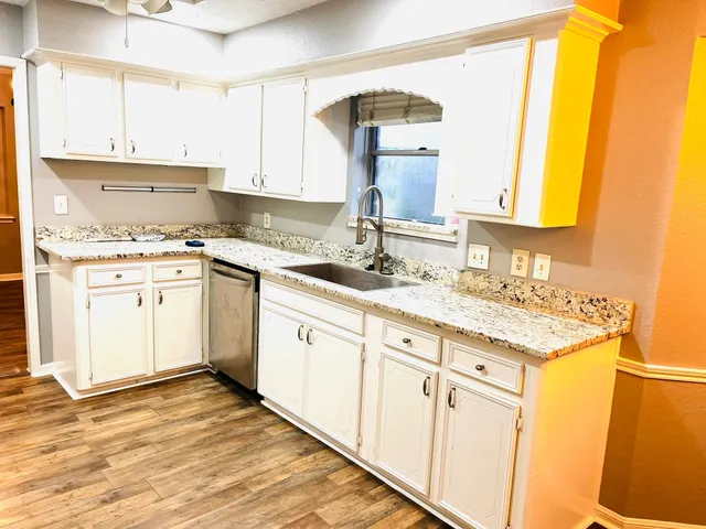 a kitchen with granite countertop a sink stove and cabinets